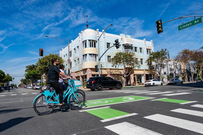 Two people riding bikeshare through an intersection with a striped bike lane.