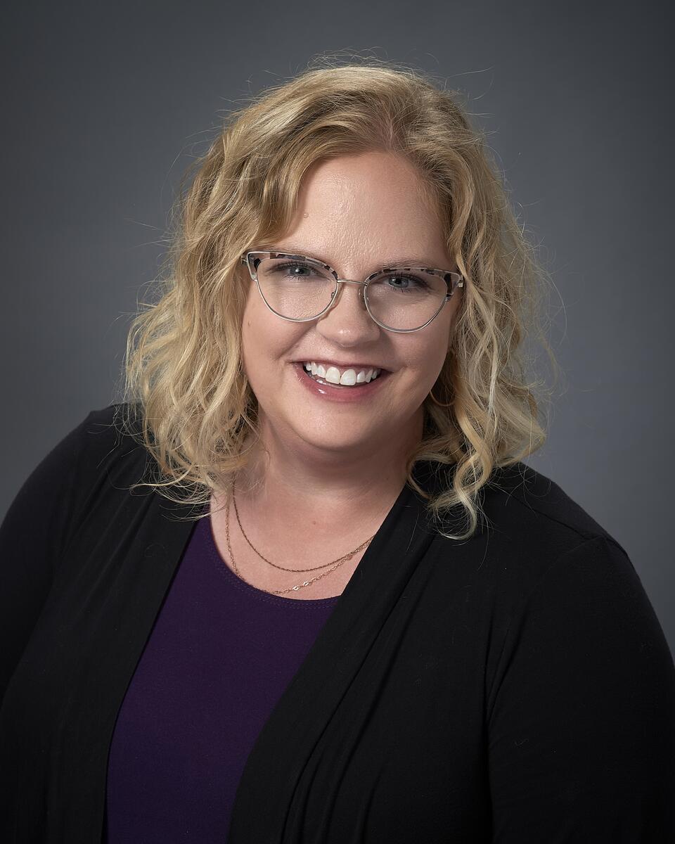 Kari smiles at the camera in front of a gray backdrop