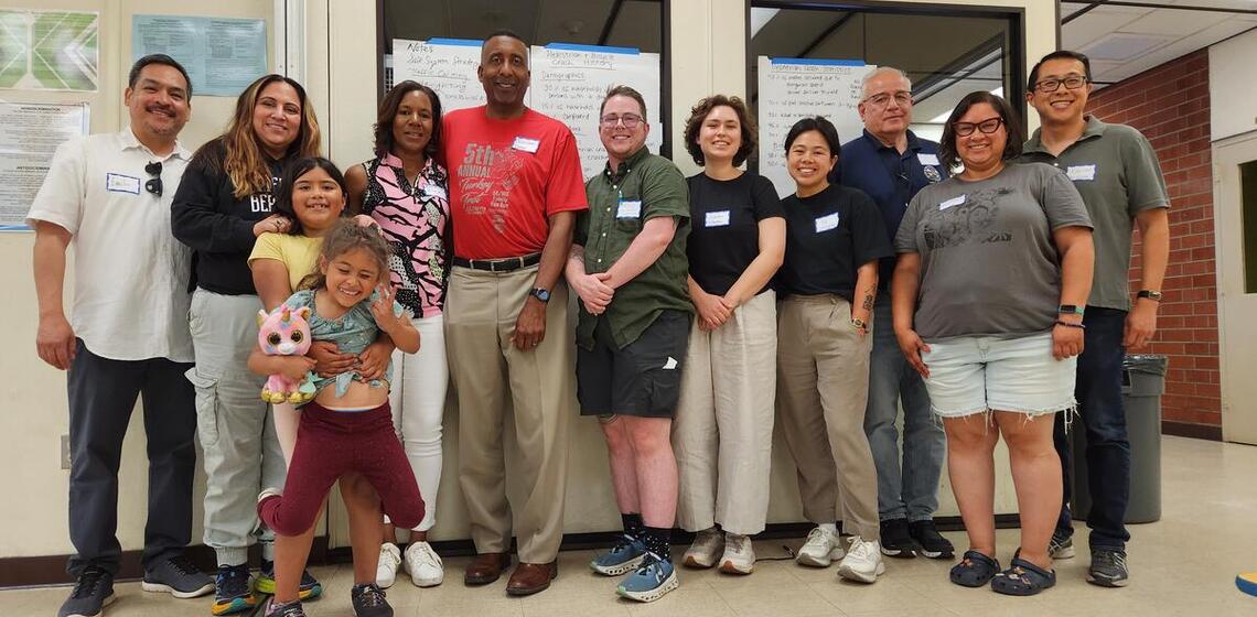 Twelve workshop participants stand and smile at the camera.