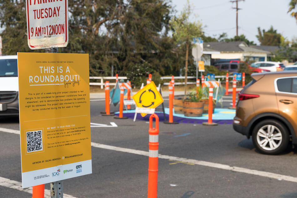 Photo with sign showing temporary roundabout as part of a week-long pilot project in Costa Mesa