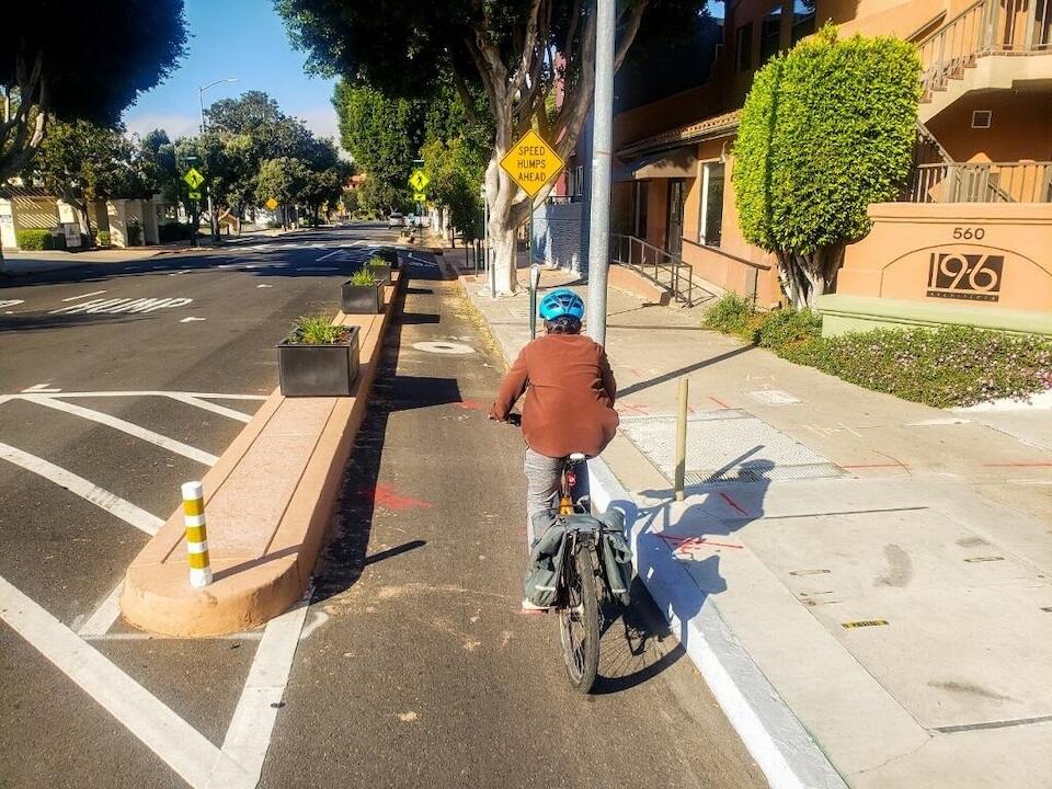 A bicyclist wearing a blue helmet biking in a protected bike lane on Higuera Street in San Luis Obispo