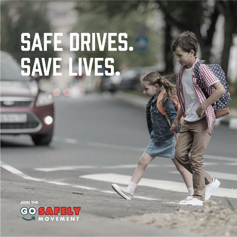 A young girl and boy in a crosswalk with the text "Safe Drives. Save Lives."