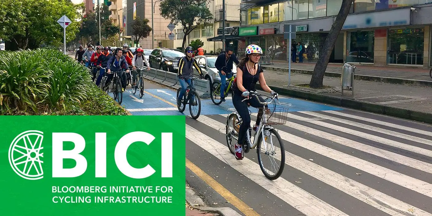 Bicyclists biking on a street with a banner that reads "Bloomberg Initiative for Cycling Infrastructure"