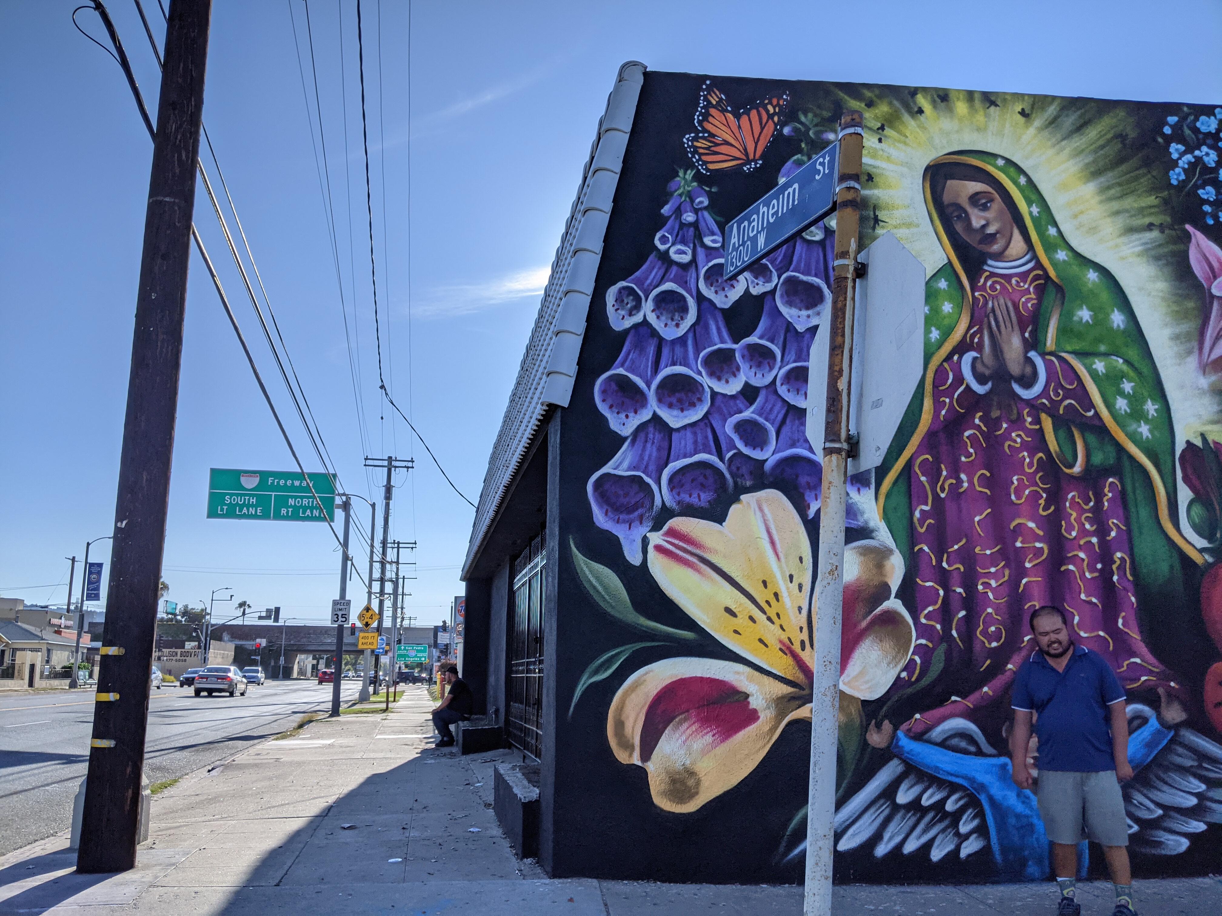 A person stands in front of a mural in Wilmington.