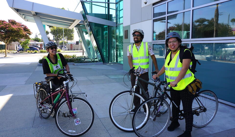 Three people smile, holding their bikes outside the meeting center for the CPBST workshop  in Willowbrook, CA